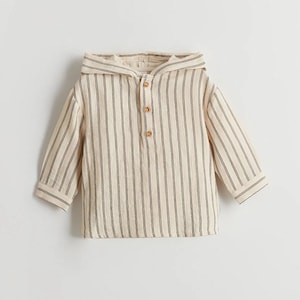 Puede incluir: Una camisa de color crema con capucha y rayas verticales negras. La camisa tiene un cierre de botón en el cuello.