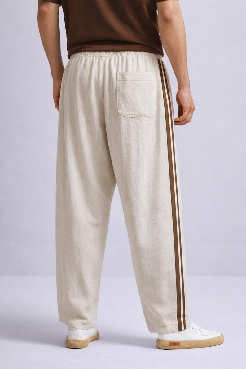 Puede incluir: Pantalones de lino beige con una raya marr&oacute;n en el lateral. Los pantalones tienen un corte holgado, un bolsillo trasero y cintura con cord&oacute;n. Se combinan con zapatillas blancas.