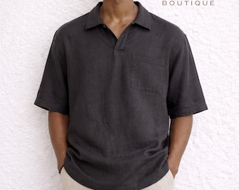 Könnte beinhalten: Ein dunkelgraues Kurzarm-Poloshirt mit Brusttasche, kombiniert mit hellbeigen Hosen. Das Hemd hat einen Kragen. Der Text "Iron Will Boutique" wird in einer Serifenschrift angezeigt.