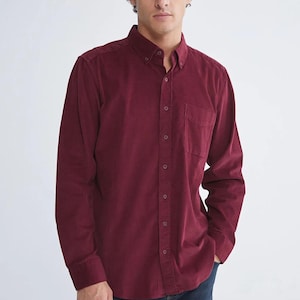 Peut inclure: Chemise en velours côtelé bordeaux avec une poche poitrine. La chemise à manches longues a un col boutonné et des boutons sur le devant. Le tissu est doux et texturé.