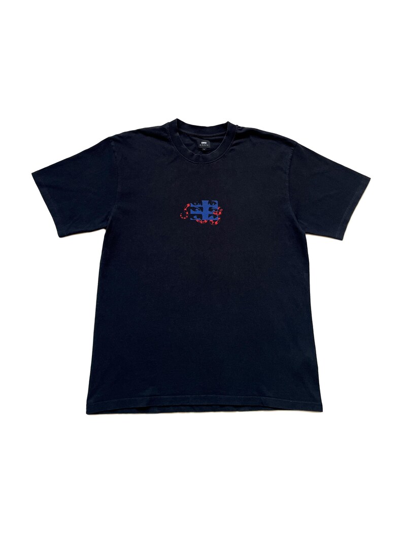 K&ouml;nnte beinhalten: Ein marineblaues T-Shirt mit Rundhalsausschnitt und kurzen &Auml;rmeln. Das Shirt hat ein kleines, abstraktes Design in der Mitte mit blauen und roten Formen. Das T-Shirt ist aus einem weichen, wahrscheinlich Baumwollmaterial.