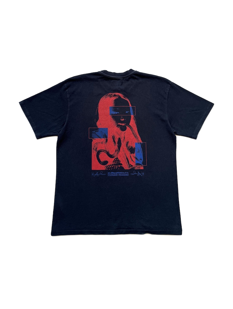 K&ouml;nnte beinhalten: Schwarzes T-Shirt mit einer rot-blauen Grafik eines Frauengesichts. Das Design beinhaltet rechteckige Bl&ouml;cke und Text am unteren Rand. Ein l&auml;ssiges Kleidungsst&uuml;ck.