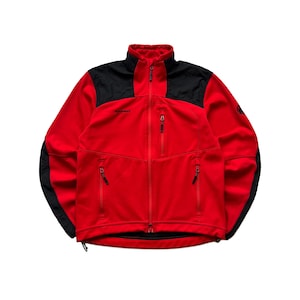 May include: A red and black fleece jacket with a full-length zipper. The jacket has a high collar and black panels on the shoulders and upper back. There are two zippered pockets on the front and a small logo on the chest.