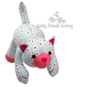 May include: A blue and white fabric cat with pink ears and nose. The cat has a daisy pattern on its body. The cat is lying on its belly with its head raised and its paws outstretched. The cat is a handmade plush toy.