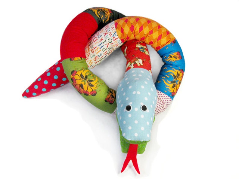 May include: A colorful patchwork snake toy made of fabric with a blue and white polka dot tail and a green, red, and blue head. The snake is curled into a circle.