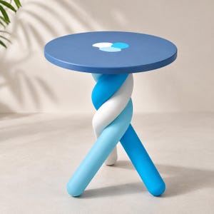 May include: A round side table with a matte blue top featuring a central white and light blue circular accent. The base consists of three thick, intertwined legs in alternating shades of white, light blue, and medium blue, creating a twisted form.