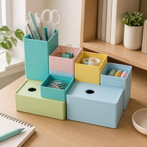 May include: A modular desk organizer set featuring stackable plastic containers in pastel shades of teal, light green, pink, yellow, and light blue. The set includes tall pen holders, shallow trays for paper clips and binder clips, and lidded boxes.