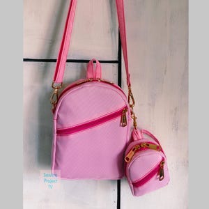 May include: A pink backpack and matching mini backpack with gold-colored zippers and hardware. The larger backpack has a diagonal zipper and adjustable straps. The mini backpack is attached with a gold chain. The text "Sewing Project TV" is visible.