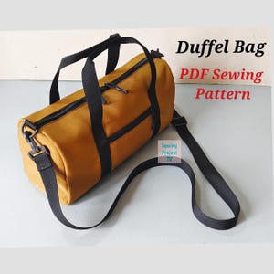 May include: A mustard yellow cylindrical duffel bag with black webbing straps, black zips, and a detachable shoulder strap. The text "Duffel Bag PDF Sewing Pattern" and a small "Sewing Project TV" logo are visible in the background.