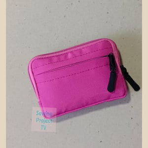 Może przedstawiać: Mała różowa kosmetyczka z zamkiem błyskawicznym i dwoma przegródkami. Kosmetyczka wykonana jest z miękkiej, fakturowanej tkaniny.