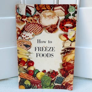 May include: Vintage cookbook cover titled "How to Freeze Foods." The cover features a collage of colorful food items, including cakes, pies, fruits, and vegetables. The title is in bold, black font against a white background.