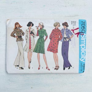 Op de afbeelding: Vintage Simplicity naaipatroon met illustraties van damesmode-ontwerpen. Het patroon toont tekeningen van outfits, waaronder een geruite jas, een lange witte jas, een groene jurk en een rode bloemenjurk. Het patroon is gemarkeerd met "7050" en "Small Size 8-10 Miss".