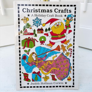 May include: A vintage Christmas Crafts book with a colorful illustration. The cover features Santa Claus, an angel, and various holiday-themed images. The title is "Christmas Crafts: A Holiday Craft Book" by Judith Hoffman Corwin.