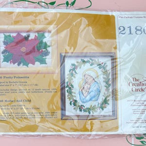 May include: A packaged cross-stitch kit featuring two framed designs. One depicts a poinsettia, the other a mother and child. The package includes the kit number 2180 and the Creative Circle logo.