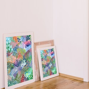 May include: Two framed prints with colorful abstract floral designs. The larger print is in a white frame and the smaller print is in a light wood frame.