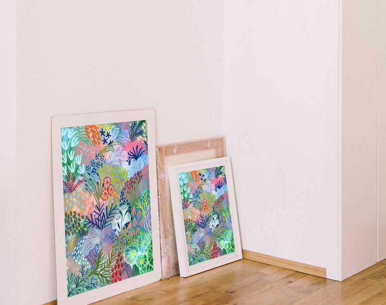 May include: Two framed prints with colorful abstract floral designs. The larger print is in a white frame and the smaller print is in a light wood frame.