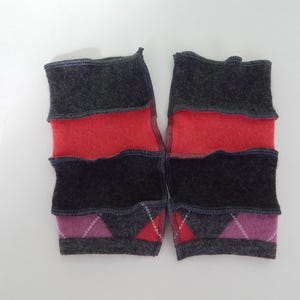 May include: A pair of handmade, colorful leg warmers. The leg warmers are made of gray, red, black, and purple felted wool. The design includes argyle patterns and contrasting color blocks. The edges are stitched with dark gray thread.