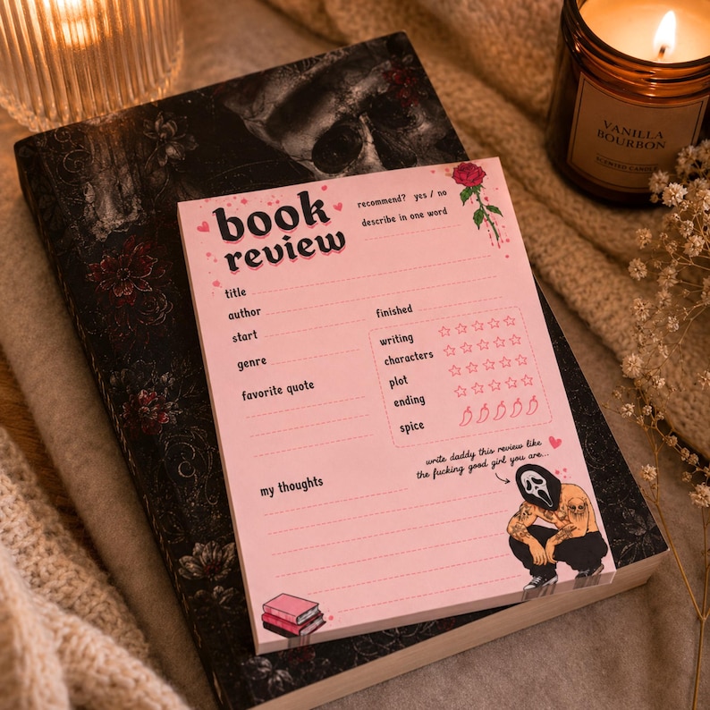 K&ouml;nnte beinhalten: Ein rosa Notizblock f&uuml;r Buchrezensionen mit einer von Scream inspirierten Illustration, der auf einem dunklen Buch mit floralen Mustern liegt. Der Notizblock enth&auml;lt Abschnitte f&uuml;r Titel, Autor und Bewertungen. Eine Kerze und eine brennende Kerze befinden sich im Hintergrund.