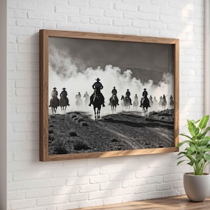 Puede incluir: Una fotografía en blanco y negro de un grupo de vaqueros montando a caballo a través de un paisaje polvoriento. Los vaqueros están silueteados contra un cielo nublado, y los caballos levantan polvo mientras galopan.