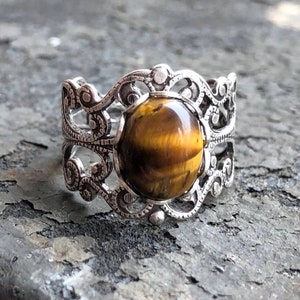 Antiqued silver filigree adjustable rings in vintage style with a tiger's eye cabochon set on a bezel.