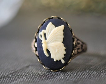 May include: A ring with a dark blue cameo featuring a white butterfly design.