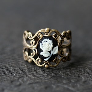 Antiqued brass adjustable filigree ring in vintage-style with a black and white single rose small cameo set in a bezel mounted on the front.