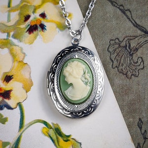 Puede incluir: Un collar de plata con un medallón verde con un camafeo que representa el perfil de una mujer. El camafeo está engastado en un marco de plata con un diseño detallado.