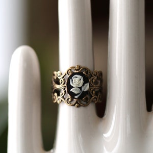 Antiqued brass adjustable filigree ring in vintage-style with a black and white single rose small cameo set in a bezel mounted on the front.