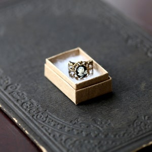 Antiqued brass adjustable filigree ring in vintage-style with a black and white single rose small cameo set in a bezel mounted on the front.