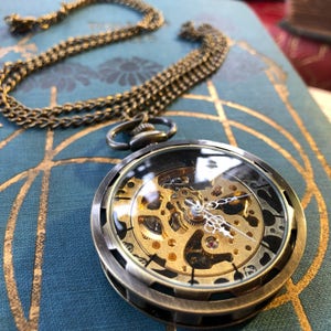 Brass bronze colored mechanical pocket watch on a necklace chain or fob.