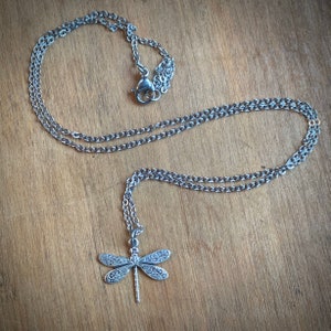 Dainty silver dragonfly necklace on 18 inches of chain.