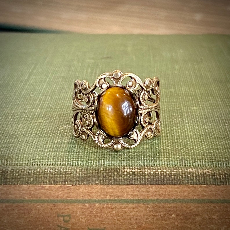 Antiqued brass filigree adjustable rings in vintage style with a tiger's eye cabochon set on a bezel.