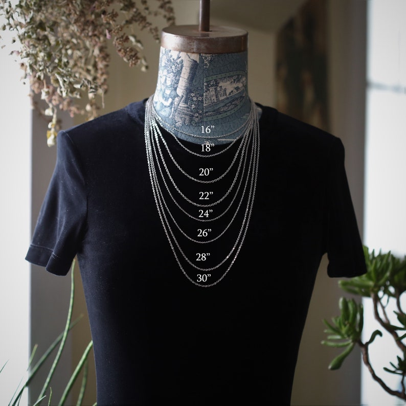 May include: A silver chain necklace on a black mannequin, showing different lengths from 16 inches to 30 inches.