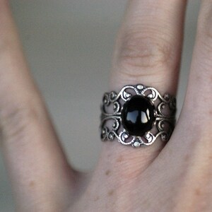 Antiqued silver adjustable filigree ring in vintage-style with a black onyx stone mineral oval cabochon set in a bezel mounted on the front.