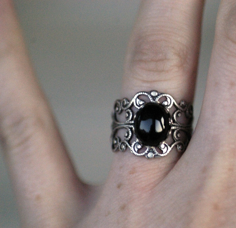 Antiqued silver adjustable filigree ring in vintage-style with a black onyx stone mineral oval cabochon set in a bezel mounted on the front.