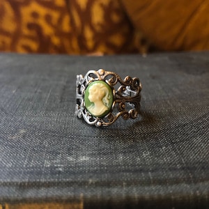 Antiqued silver adjustable filigree ring in vintage-style with a green and cream small lady cameo set on a bezel.