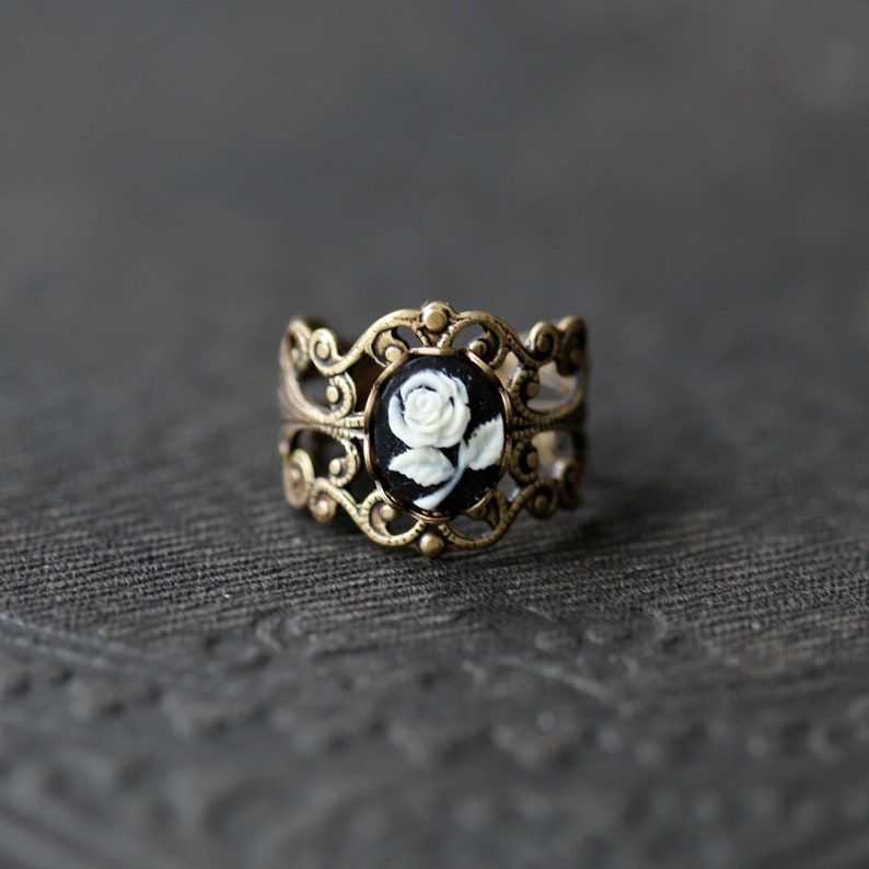 Antiqued brass adjustable filigree ring in vintage-style with a black and white single rose small cameo set in a bezel mounted on the front.