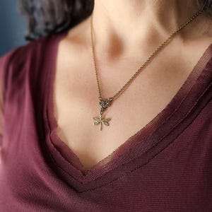 Antiqued brass filigree small dragonfly necklace in vintage syle on a chain with a connector modeled at 18 inches.