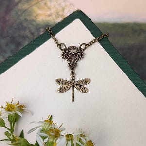 Antiqued brass filigree small dragonfly necklace in vintage syle on a chain with a connector.