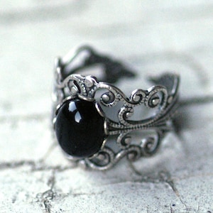 Antiqued silver adjustable filigree ring in vintage-style with a black onyx stone mineral oval cabochon set in a bezel mounted on the front.