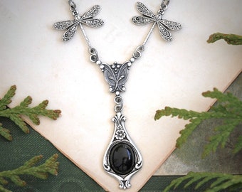 May include: A silver necklace with a black gemstone pendant and dragonfly accents.