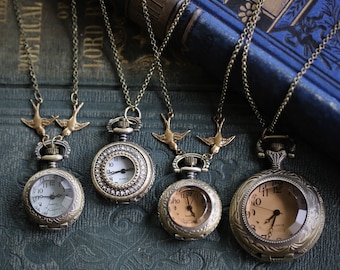 May include: Five antique-style pocket watches on chains with bird charms. The watches have different colored faces and are arranged on a blue and green patterned surface.
