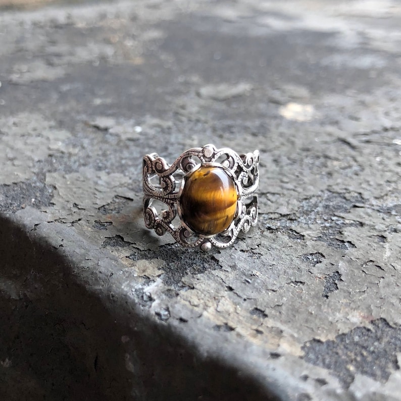 Antiqued silver filigree adjustable rings in vintage style with a tiger's eye cabochon set on a bezel.