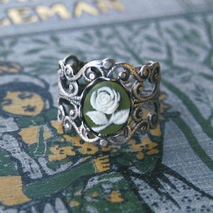 Green and white small rose cameo set in a bezel on an antiqued silver adjustable filigree ring in vintage-style.