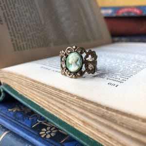 Antiqued brass and silver adjustable filigree ring in vintage-style with a green and cream small lady cameo set on a bezel.