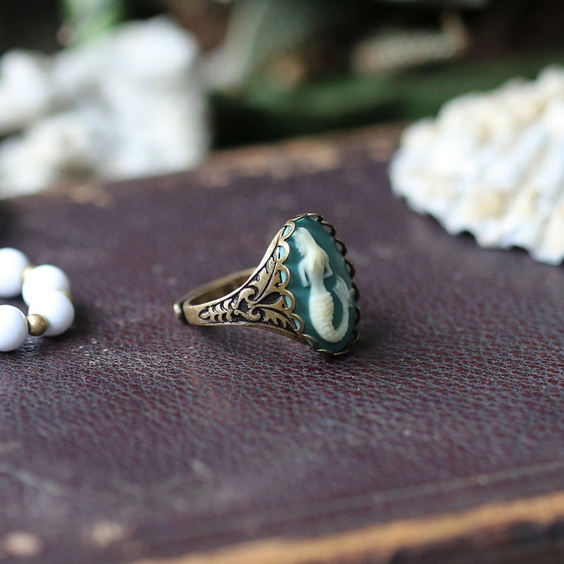 Antiqued brass adjustable vintage style ring with a blue and cream mermaid cameo side view.