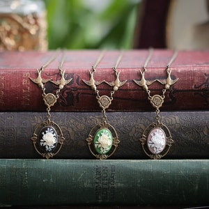 Tio of antiqued brass bird necklace blossom cameos in black, green and pink.  set on an embellished vegetative floral setting.  For sale from ragtrader vintage
Secret garden or Beauty and the Beast style.