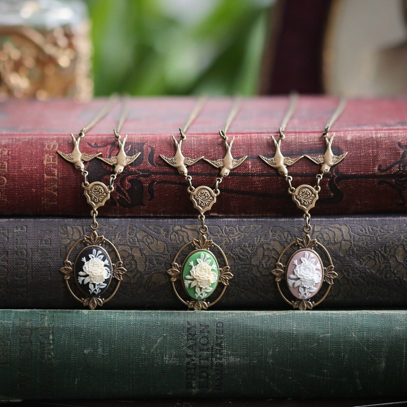 Tio of antiqued brass bird necklace blossom cameos in black, green and pink.  set on an embellished vegetative floral setting.  For sale from ragtrader vintage
Secret garden or Beauty and the Beast style.