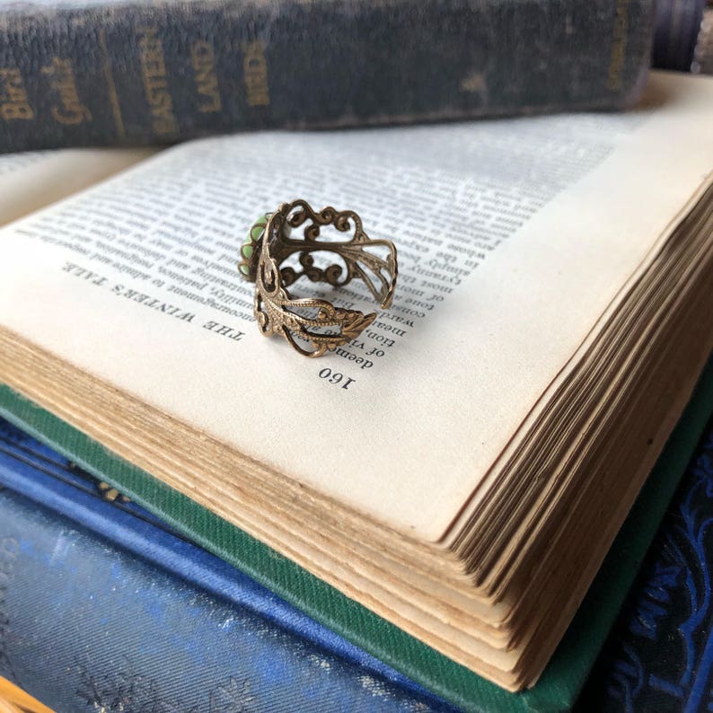 Antiqued brass and silver adjustable filigree ring in vintage-style with a green and cream small lady cameo set on a bezel. Rear view.