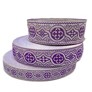 Peut inclure: Trois rouleaux de galon violet et argent avec un motif géométrique. Le galon est tissé avec un motif répété de croix et de diamants.